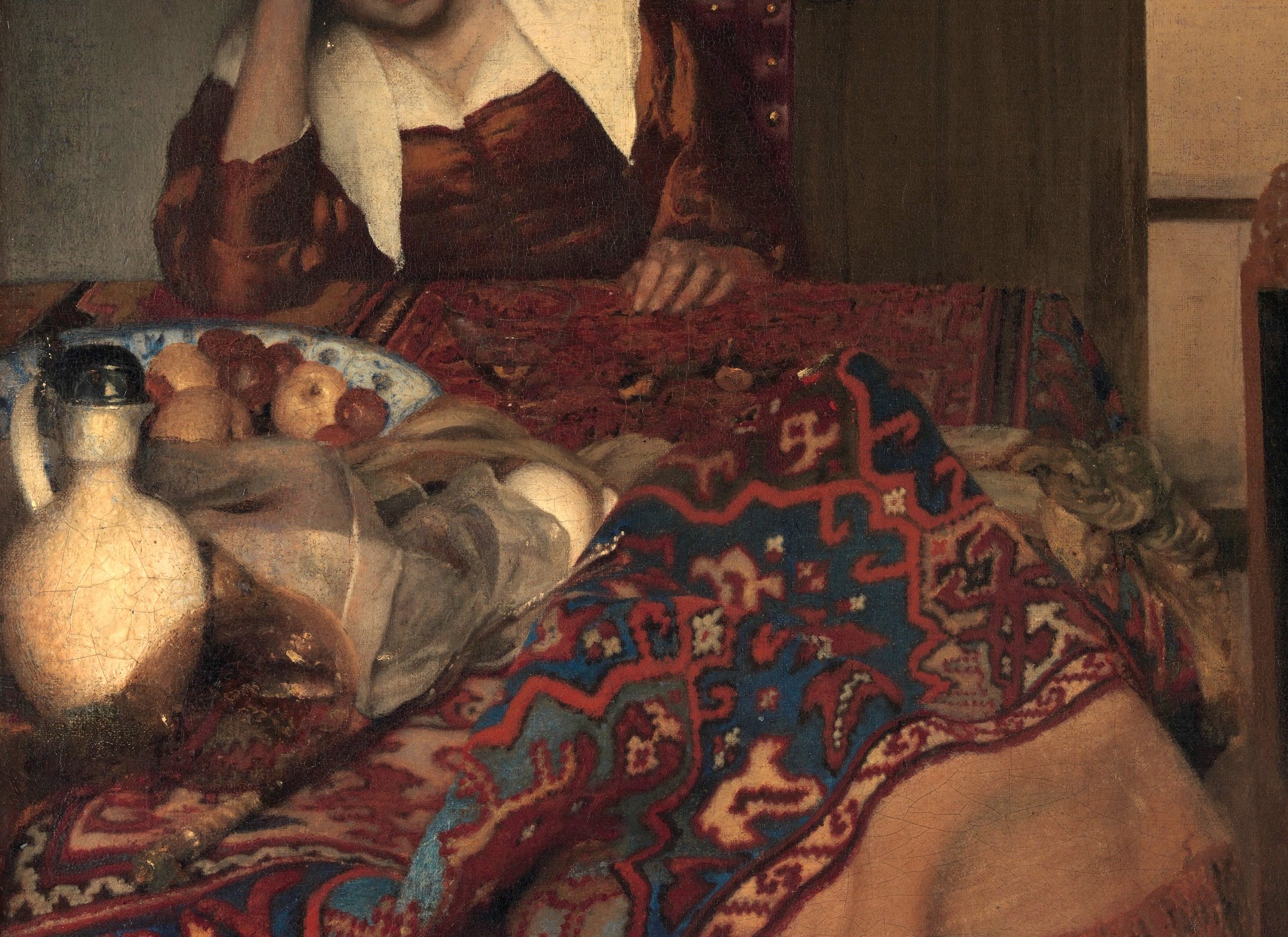 A status symbol in Dutch interiors; the dense reds, blues, and cream medallion patterns hint at trade wealth and also anchor the lower half of the composition