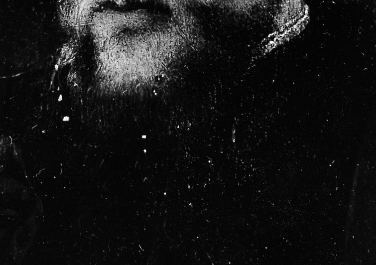 His dark garment and hat were typical of the era.