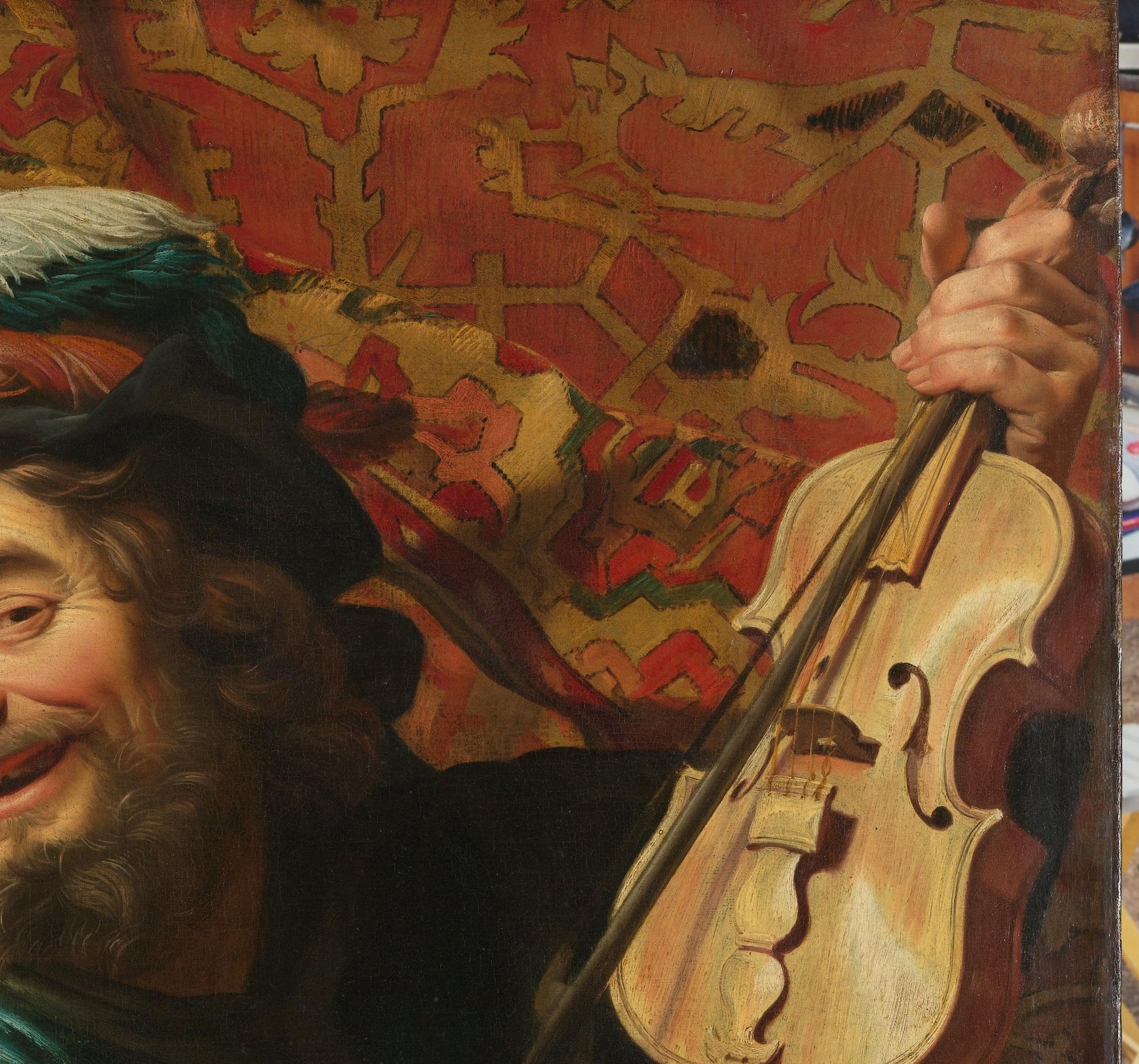 The fiddler appears to emerge from behind a rich tapestry.