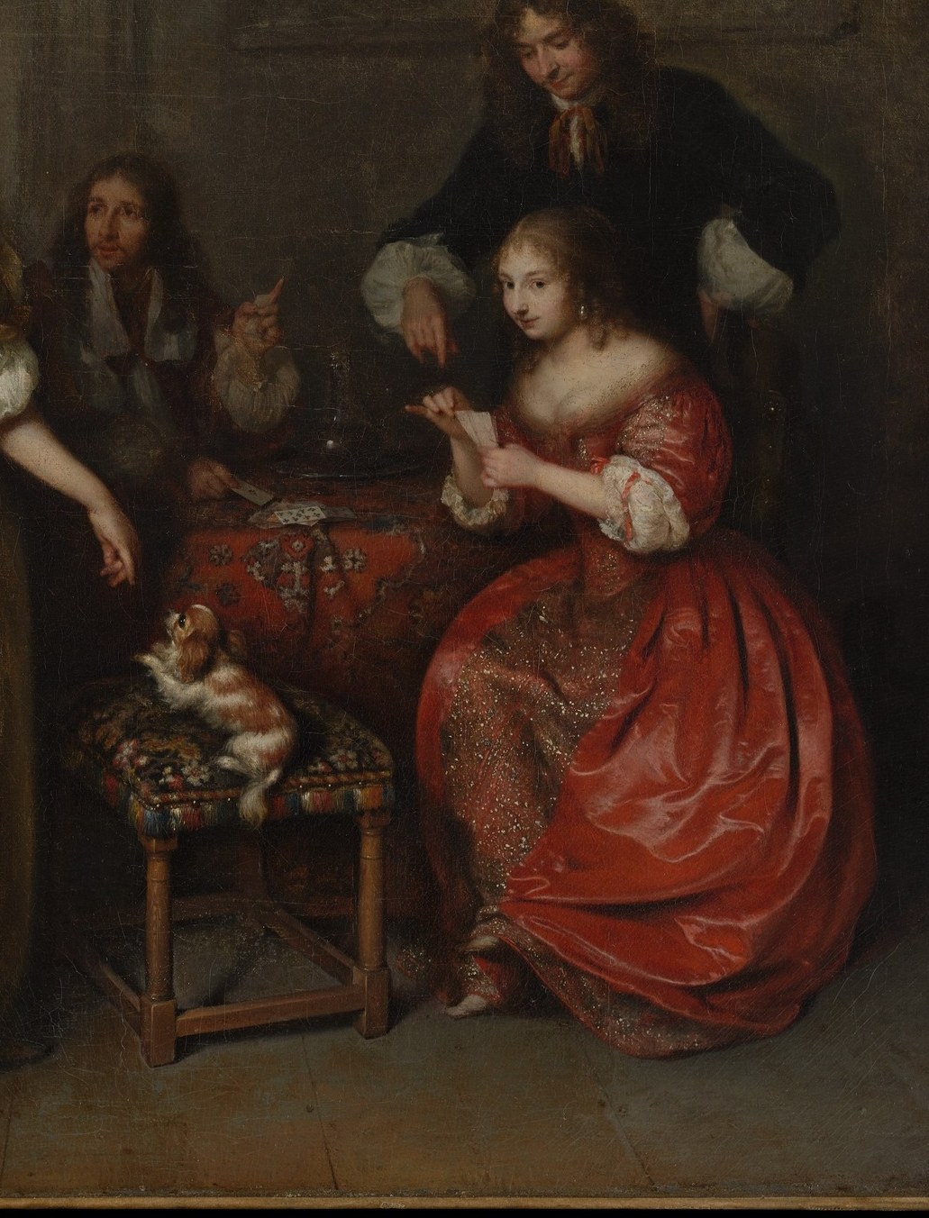 Her vivid red acts as chromatic counterpoint to the gold dress; she is the active player and her downward gaze keeps the viewer uncertain about the strength of her hand.