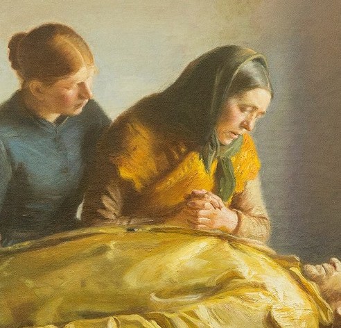 A woman in a yellow shawl clasps her hands in sorrow.