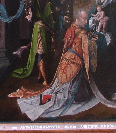 His elaborate robes and bowed head convey deep reverence and humility.