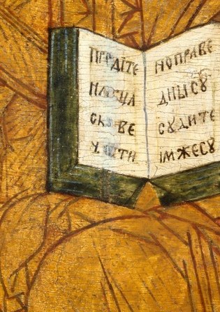Holds indistinct text, symbolizing divine scripture and Christ's role as the bearer of knowledge.