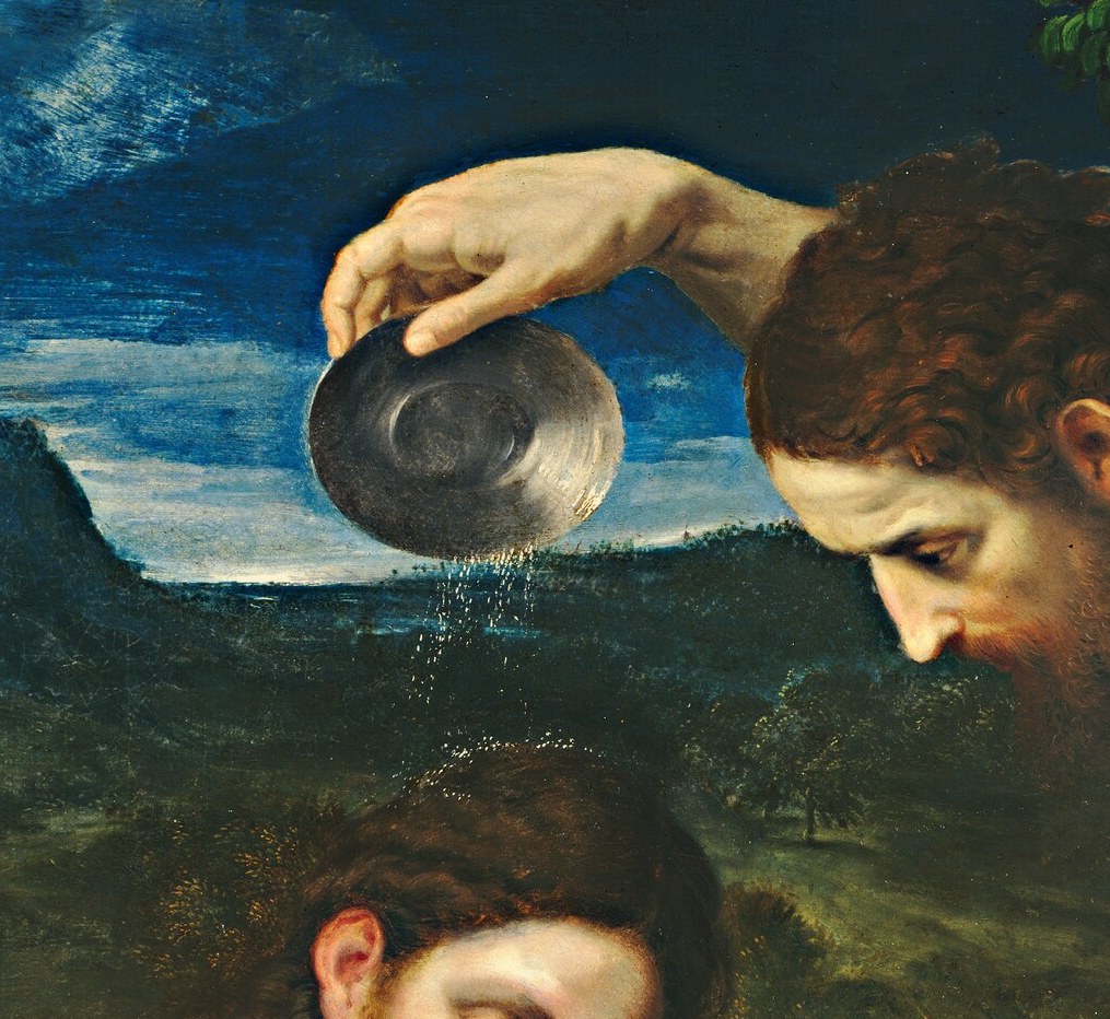 A man kneels in a river, eyes closed.