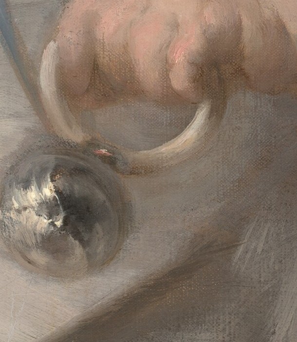 The little silver rattle is loosely held.