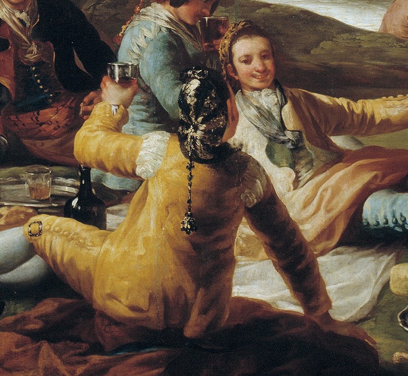His relaxed posture and interaction with others highlight the social aspect of the picnic.