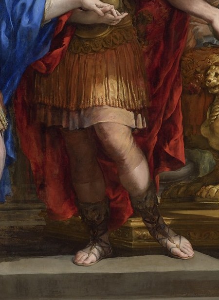 His armor shows his strength, but his gaze is downcast.