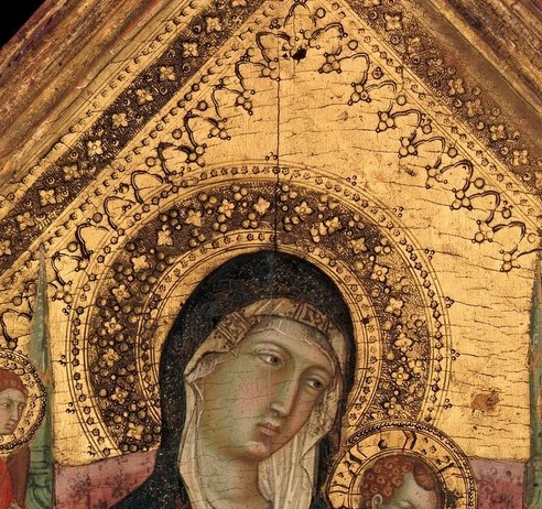 Holds a scroll in the left hand, gestures blessing with the right , the dual nature of Christ (teacher and savior) compressed into an infant form