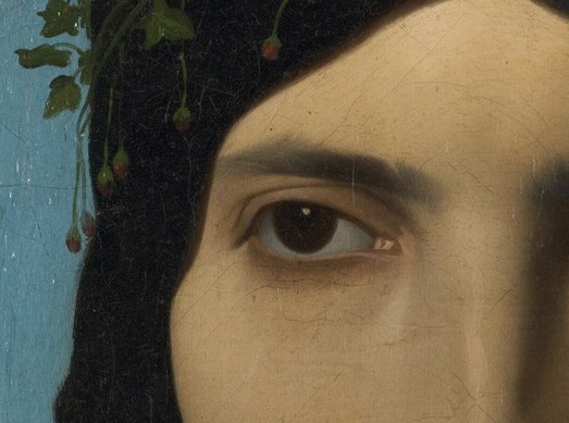 Lies in the cooler shadow half of the face; the iris catches a glint that anchors emotion despite the neutral expression