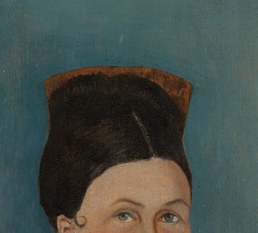The distinctive shape of the hat adds to her period attire and frames her face.