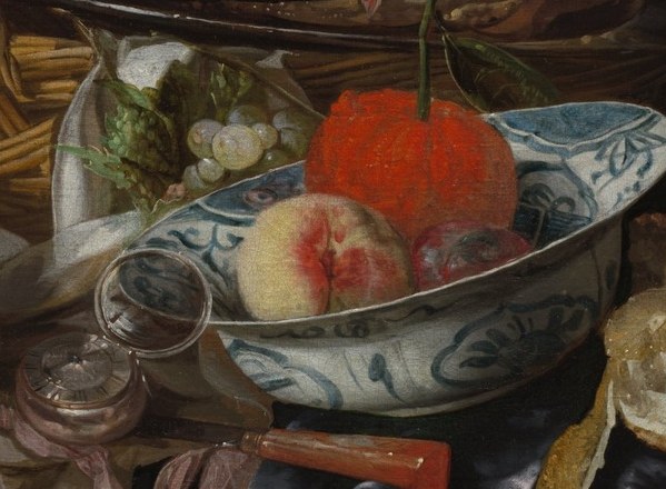 The vibrant fruit within, particularly the red apple, contrasts with the delicate pattern of the bowl, adding color and life.