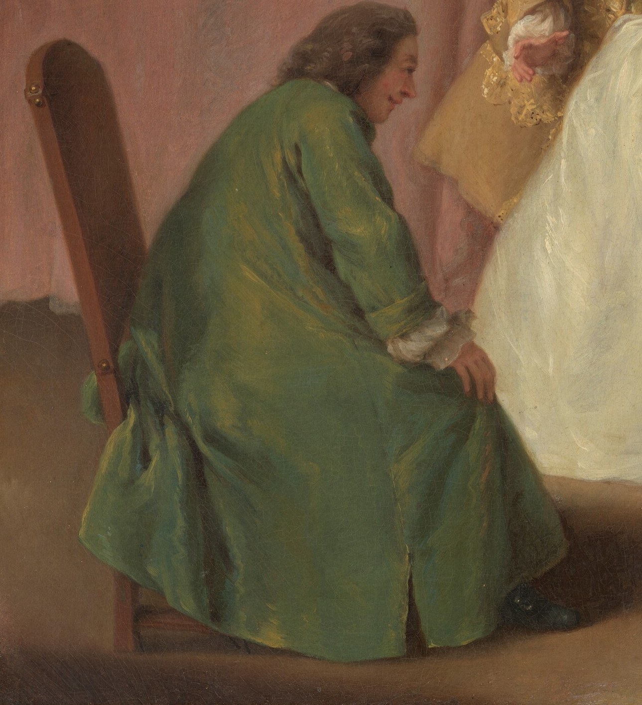 His posture and focus on a small object suggest he is participating in or observing the game.