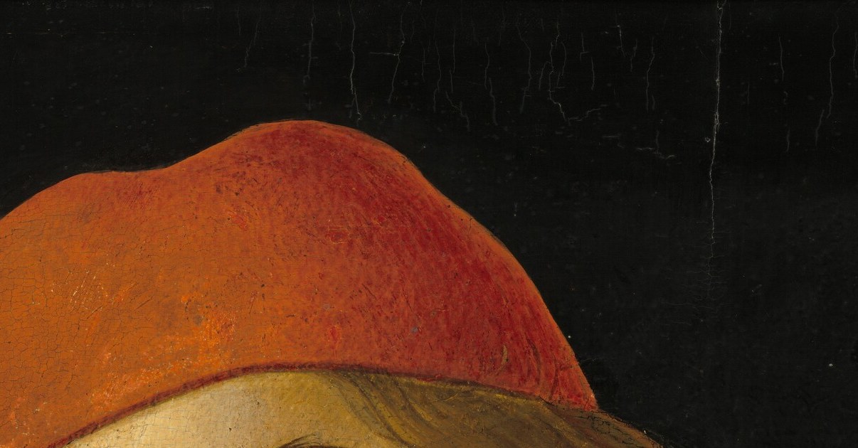 The vivid crimson cap against the dark background is a deliberate color accent; its cut identifies the wearer as a Florentine merchant-class youth of the 1480s.