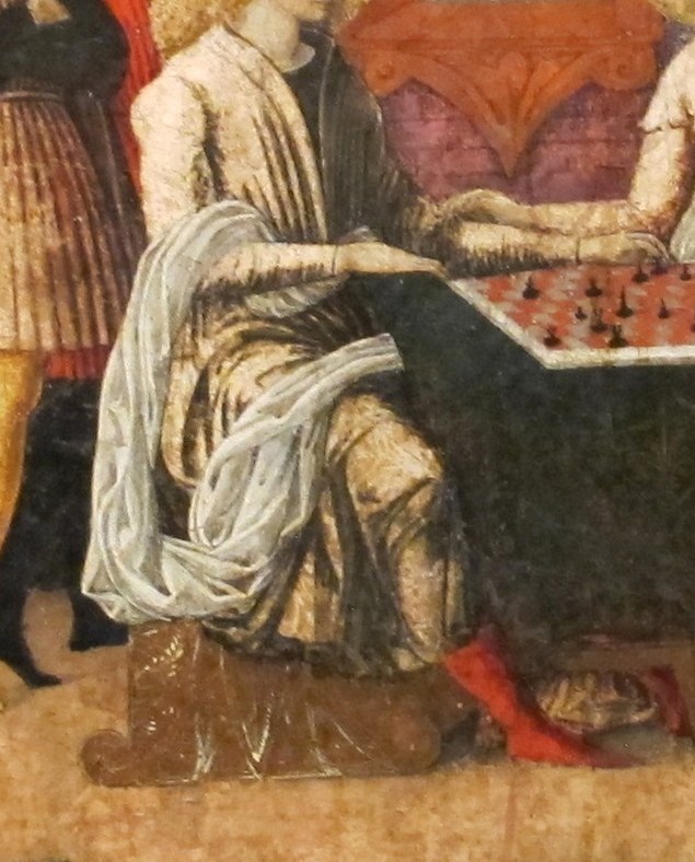 His focused expression and hand position on the board reveal his engagement in the strategic game.