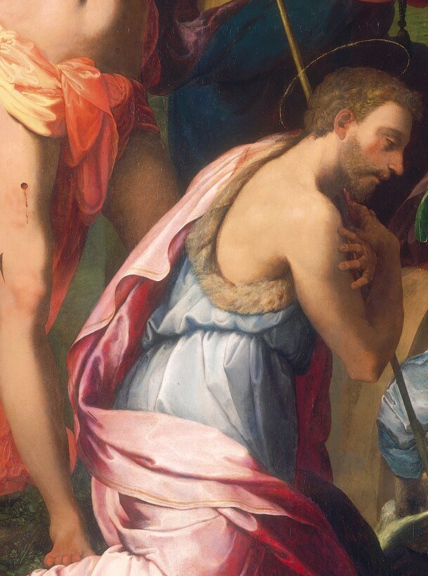 His camel-skin garment and fervent kneeling posture prefigure the Baptism; his presence ties nativity to the adult Christ's story