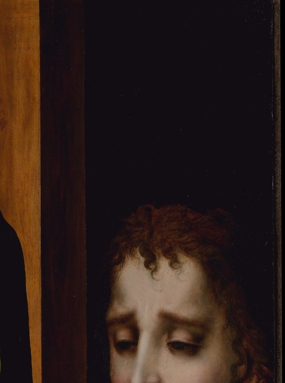 His compressed brow and downward gaze perform masculine grief restrained , a deliberate counter-pose to the women's more open mourning, readable only when the camera lingers.