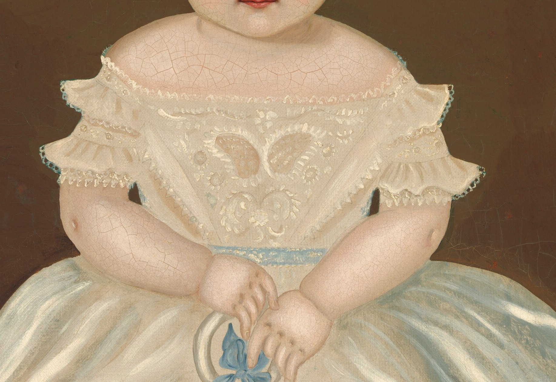 The delicate lace and ruffles suggest a preciousness and care associated with childhood.