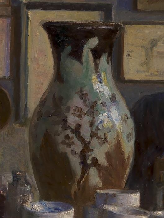 A vibrant vase sits on his cluttered desk.