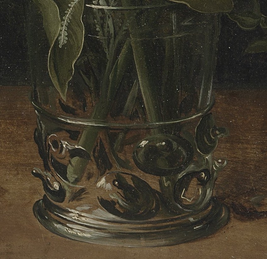 The detailed metalwork on the vase shows the artist's skill and adds a touch of luxury, contrasting with the natural forms of the flowers.