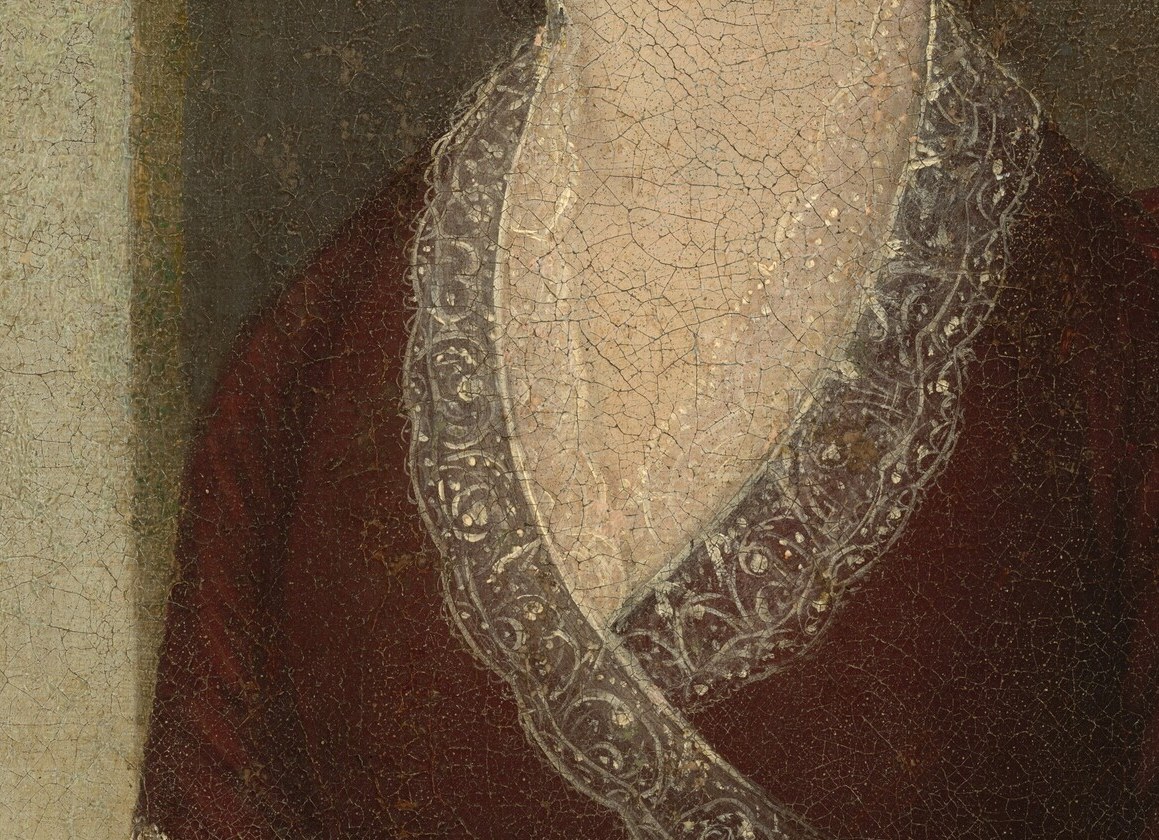 The delicate lace trim contrasts sharply with the deep crimson dress and tells us about the sitter's social standing and access to fine imported fabric.
