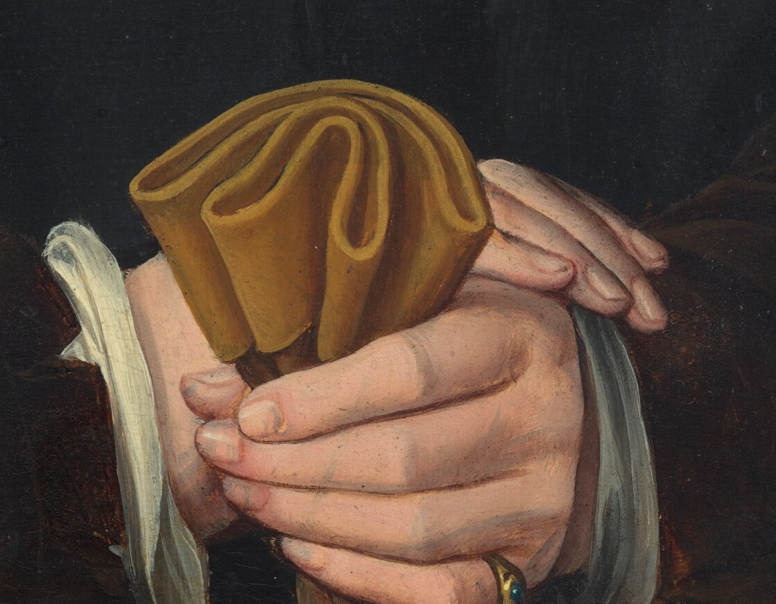 He holds a folded brown cloth. Its meaning is lost to time.