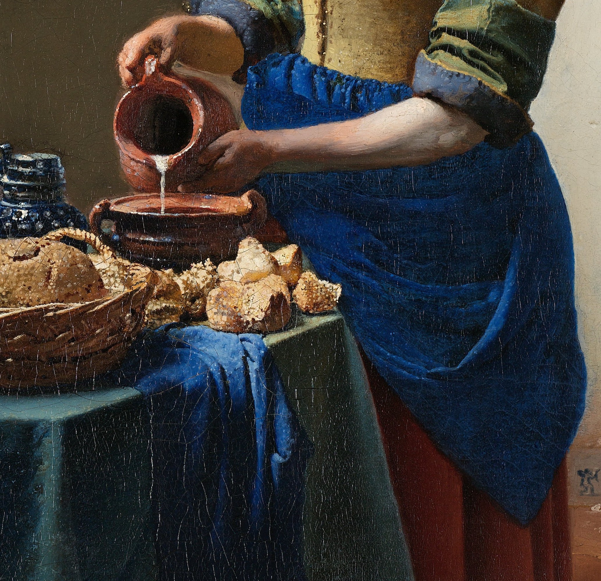 The yellow-and-blue pairing is Vermeer's chromatic signature; the blue apron functions as the painting's visual anchor, drawing the eye downward to ground the figure