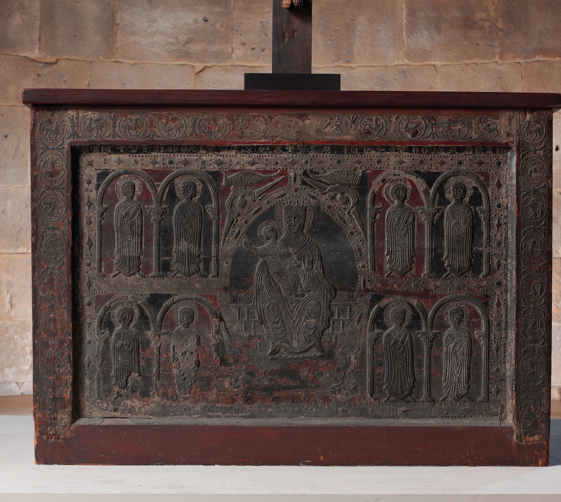 The architectural frame is transitional Romanesque-to-Gothic, a precise stylistic datemark for the 1225 attribution; carved shadow lines in the arcade spandrels are visible even in this worn state