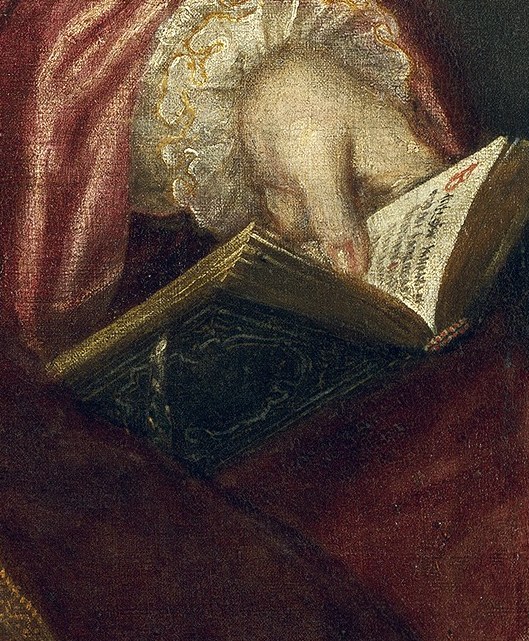 She holds a small book, suggesting her intelligence and piety.