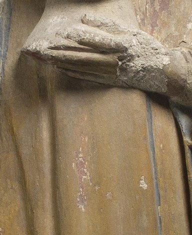 The clasped hands are a clear gesture of prayer and piety, central to the devotional aspect of the figure.