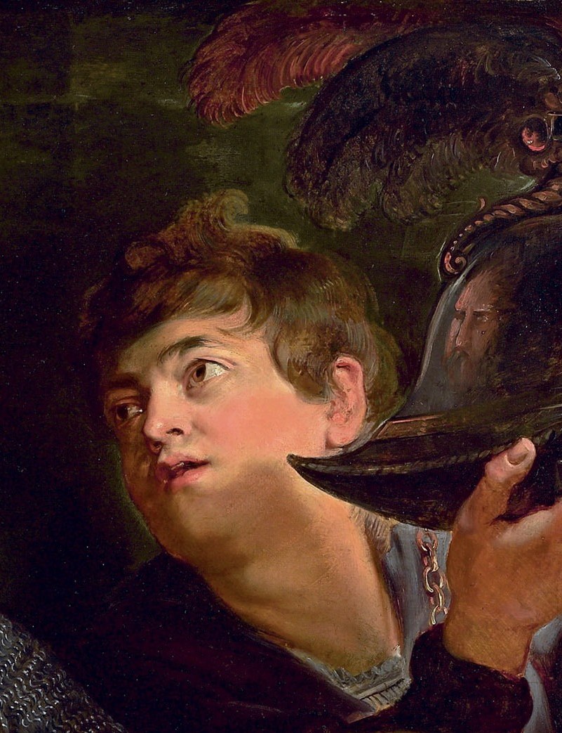 A page boy lifts his helmet. He is being armed for battle.