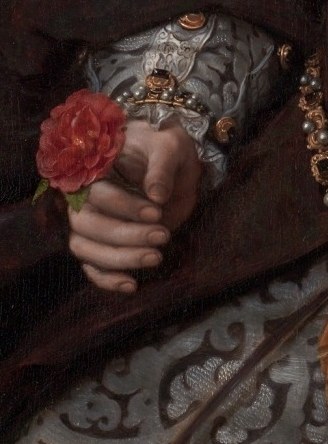 Her left hand holds a rose for love and beauty.