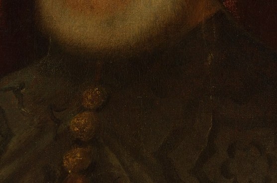 He wears a dark fur collar and ornate robe.