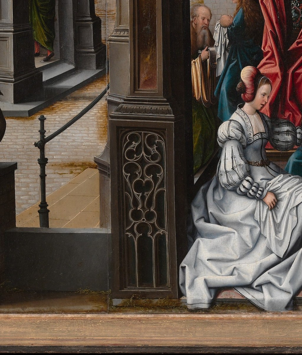 The compositional anchor of the panel; her sweeping ivory robes demonstrate Flemish mastery of volumetric fabric and echo Italian Renaissance figure types Van Orley absorbed in Brussels.