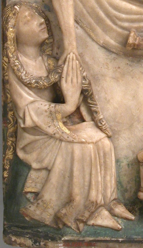 Her posture of prayer and the golden halo suggest her piety and importance in the scene.