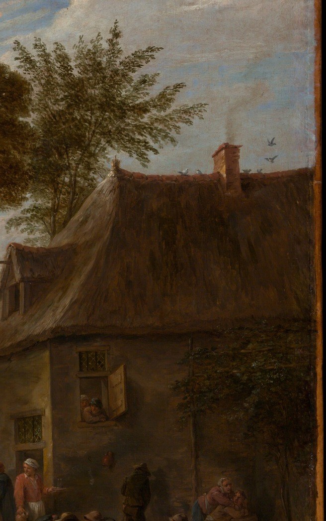 The solid built environment against which the crowd presses; its dark doorway implies interior space and shelter, anchoring the scene in a specific vernacular architecture.