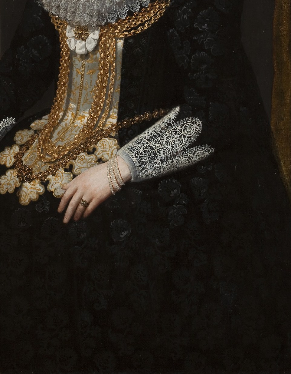 Her gown is richly embroidered with shimmering gold thread.