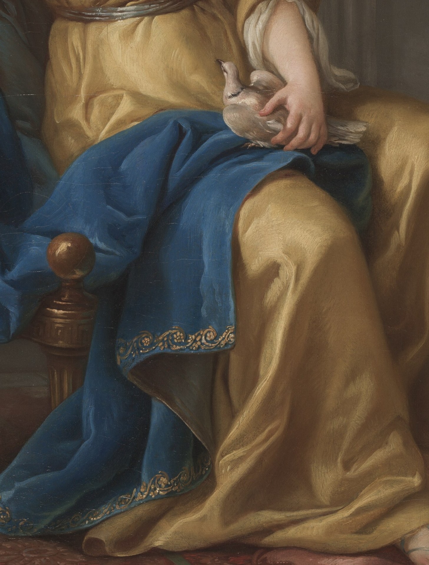 The heavy, luxurious folds of the blue fabric provide a strong visual anchor and a dramatic contrast to the woman's golden attire.