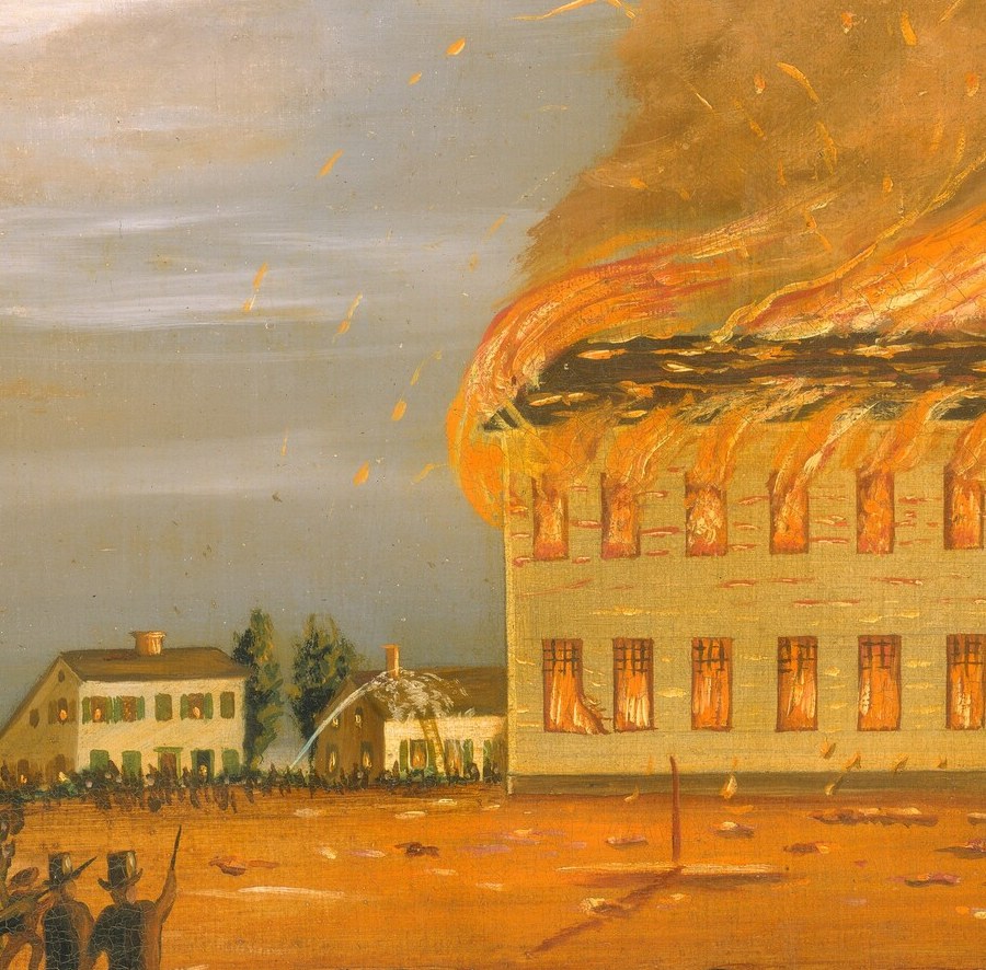 The pallid church wall still standing while fire pours from every opening creates a ghostly shell effect , the architecture resists even as the interior is wholly lost.