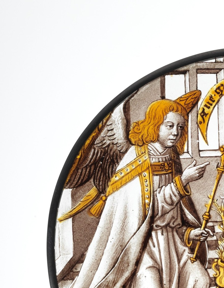 The painter stained only the wings amber-gold. Everything else is monochrome glass.