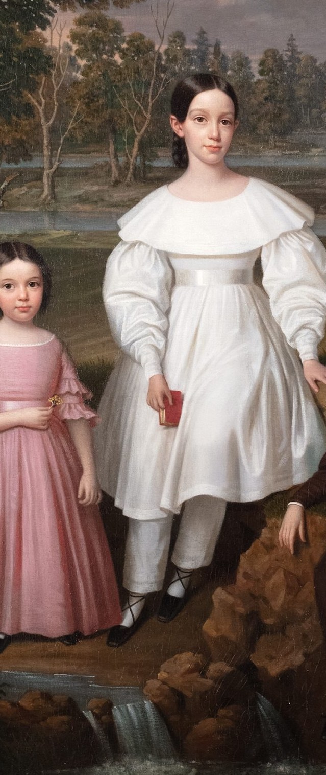 Three well-dressed children, the Freys, pose on a Louisiana riverbank.