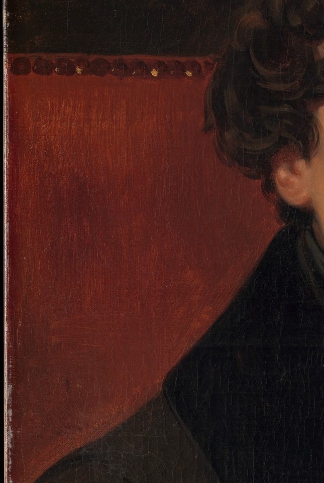 The rich red of the curtain provides a warm, textured contrast to the dark clothing and the subject's skin tones.