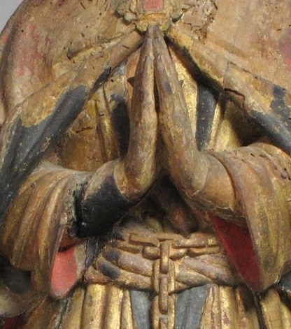 Look closely at his hands, clasped in prayer.