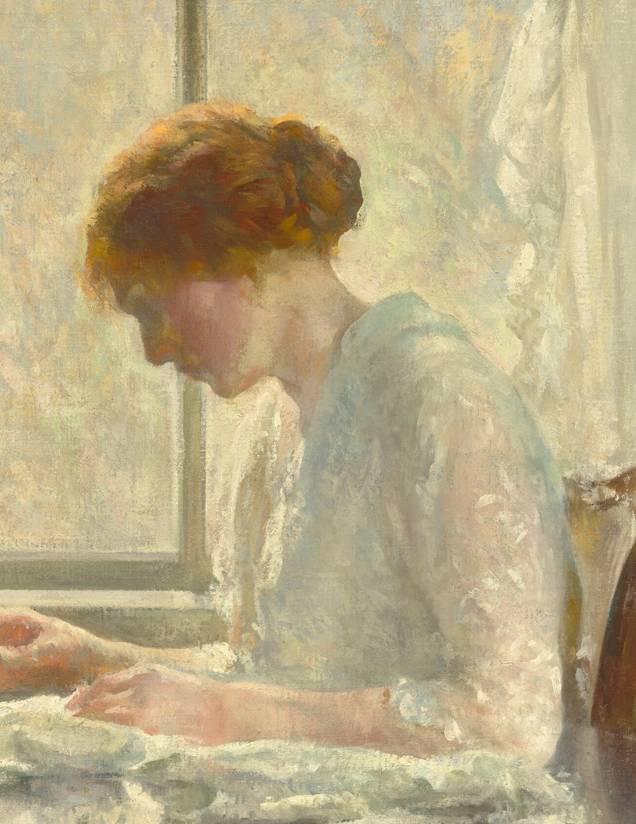 This woman is focused on her sewing, bathed in window light.
