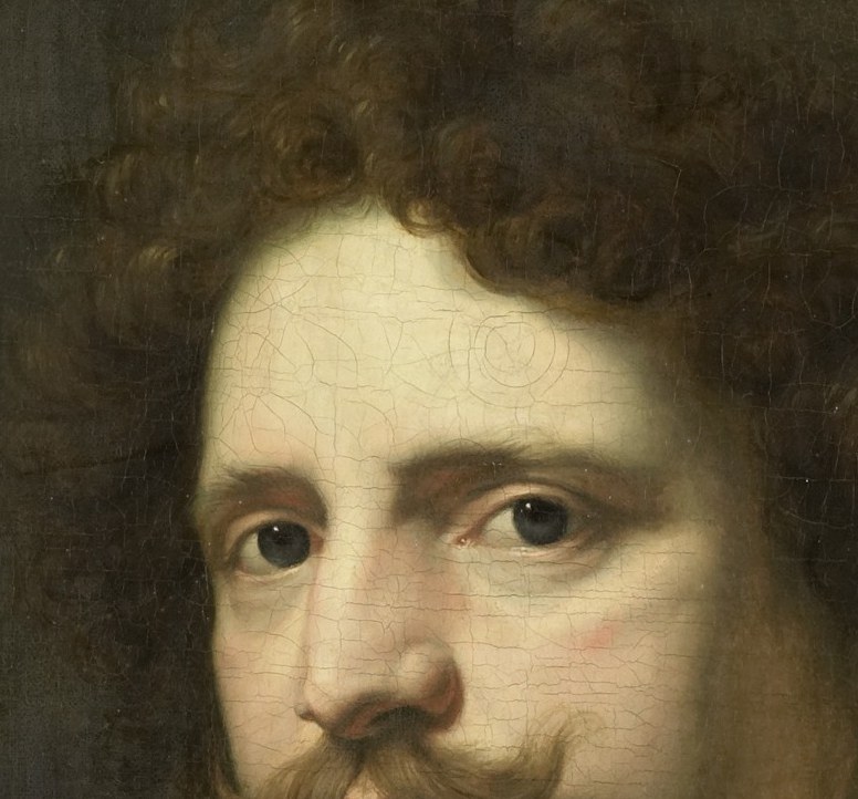 The voluminous, dark curls contrast with the lighter tones of his face, framing his features.