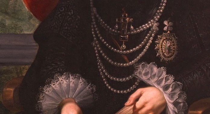 She wears pearls and a fine ruffled collar.