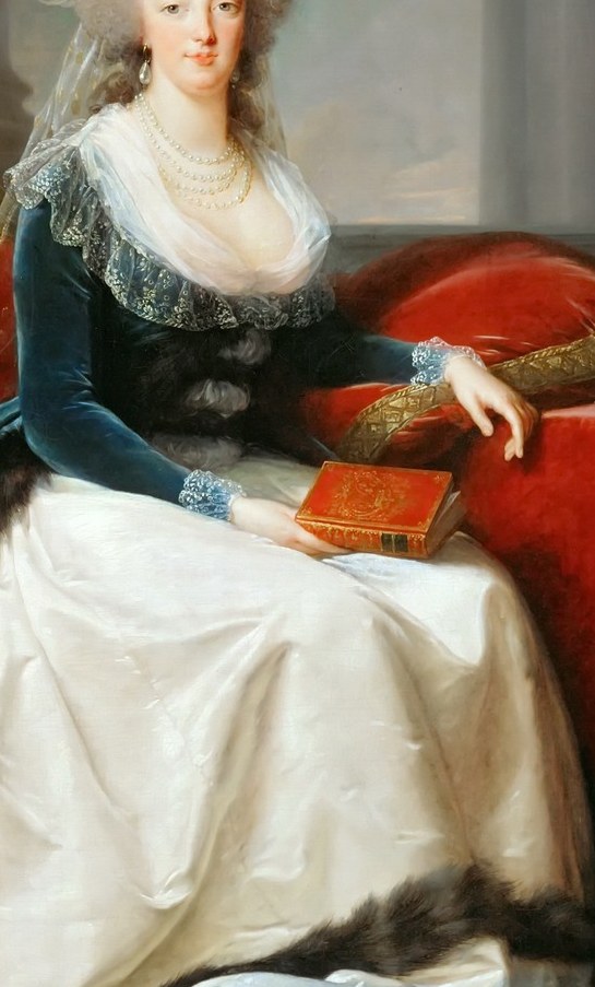 She wears a rich blue velvet coat and a white silk dress.