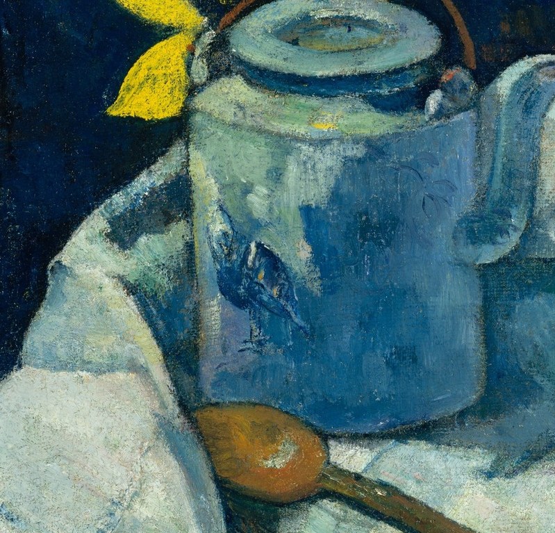 A European teapot, set against a flat blue-green wall.