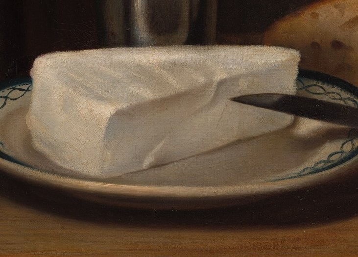 The stark white of the cheese contrasts with the plate and knife, highlighting its form and texture.
