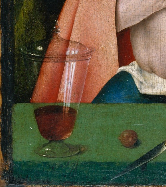 Grapes are the clearest Eucharistic symbol in the composition, echoing the wine in the glass and together forming a paired visual argument.