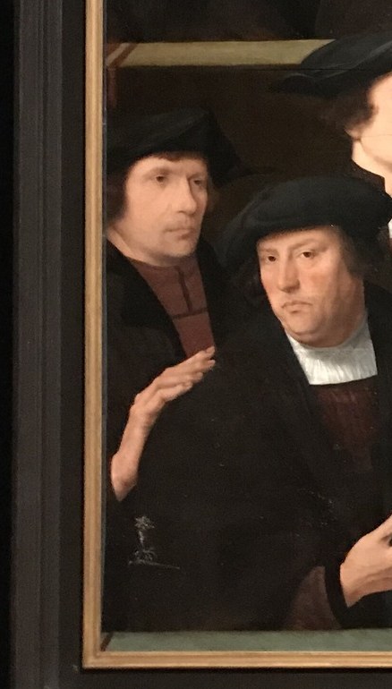 His open hands and direct gaze suggest he is speaking or making a point, drawing the viewer into the group's conversation.